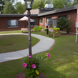 A peaceful courtyard with a garden and walking path surrounded by a brick building.