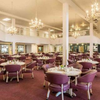 An elegant dining area with chandeliers and neatly arranged tables and chairs.