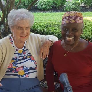 Two elderly women smiling and enjoying their time together outdoors.