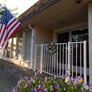A house entrance adorned with an American flag and vibrant flowers.