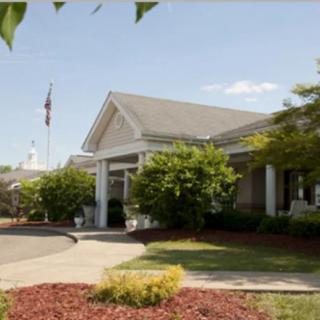 A welcoming entrance to a building surrounded by greenery and a neatly maintained garden.