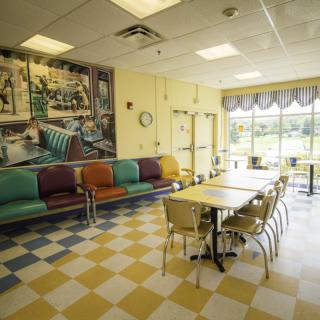 A retro-themed diner interior with colorful seating and checkered flooring.