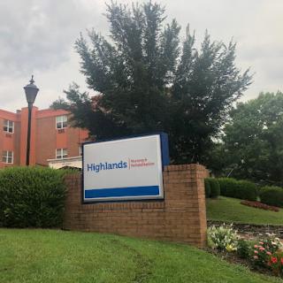 A sign for Highlands, surrounded by lush greenery and residential buildings.