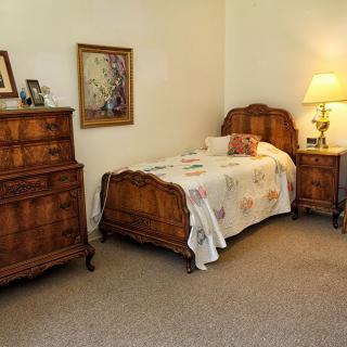 A cozy bedroom with vintage wooden furniture and a warm lamp.