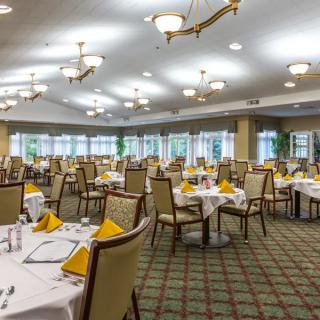 A well-lit dining area with neatly arranged tables and chairs, set for service.