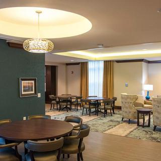 A cozy and modern dining area with elegantly arranged tables and chairs, illuminated by stylish lighting.