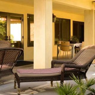 A cozy patio featuring wicker furniture and a sun lounger, perfect for relaxation.