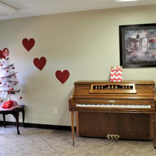 A cozy indoor space featuring a piano, decorative hearts on the wall, and a Christmas tree.