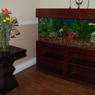 A cozy corner featuring an aquarium with colorful fish and a vase of flowers on a wooden table.