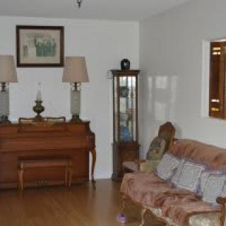 A cozy living room featuring a piano, lamps, and a sofa with cushions.