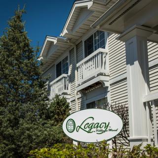 A white building with a Legacy sign, surrounded by trees under a clear blue sky.