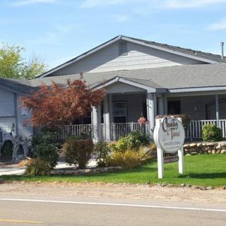 A residential house with a porch and a garden, featuring a sign in front.