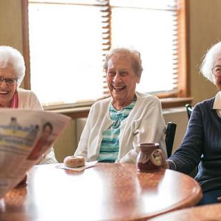 A group of elderly people enjoying a social gathering around a table.