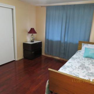 A simple bedroom with a bed, nightstand, and lamp near a window with blue curtains.