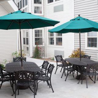 A patio with tables and chairs under green umbrellas.
