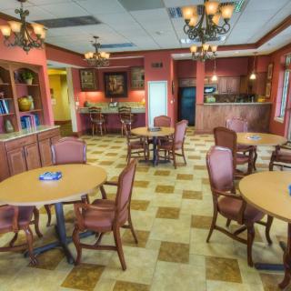 A spacious dining area with multiple tables and chairs, featuring elegant chandeliers and warm decor.