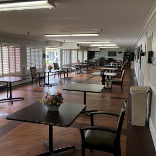 A spacious and well-lit dining area with tables set for guests, featuring a floral centerpiece.