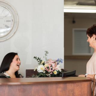 Two people having a friendly conversation at a reception desk.