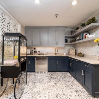 A modern kitchen featuring blue cabinets, patterned flooring, and open shelves with decorative items.