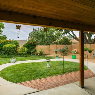 A well-maintained backyard with a circular lawn, brick path, and garden features.