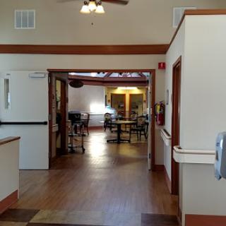 A view of a spacious hallway leading to a dining area with wooden floors and ample natural light.