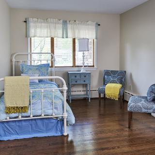 A cozy bedroom with a metal framed bed, blue accents, and wooden flooring.