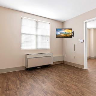 A minimalist room with a mounted TV and wooden flooring.