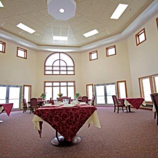 A spacious and elegantly designed restaurant interior, featuring tables adorned with tablecloths and abundant natural light.