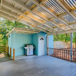 A covered outdoor patio with a grill and fenced backyard.