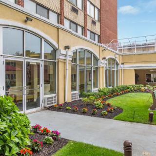 A beautifully landscaped garden area outside a modern building with large arched windows.