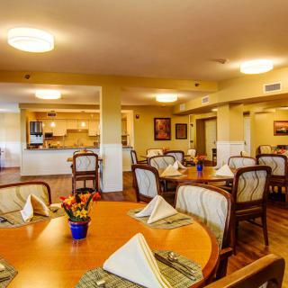 A warmly lit dining area with neatly set tables and chairs, ready for guests.