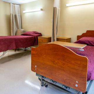An empty hospital room with two neatly made beds and privacy curtains.