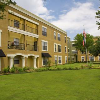 A three-story apartment building with a well-maintained lawn and balconies.