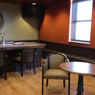 A cozy office meeting room with a small bar area and several chairs.