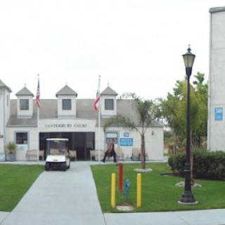A building entrance with flags, a golf cart, and a well-maintained lawn.
