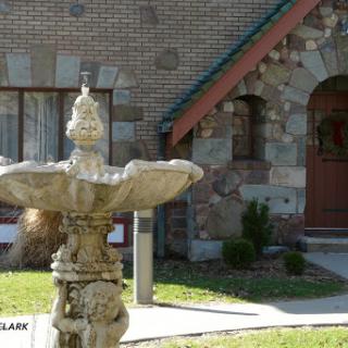 A decorative stone fountain in front of a brick building.