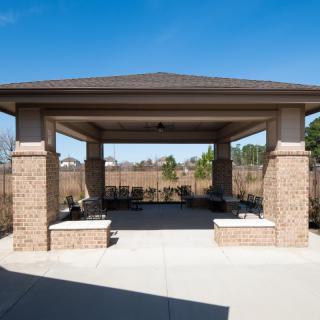 A brick gazebo with seating under a clear blue sky.