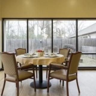 A cozy dining room with a round table and four chairs, surrounded by large windows providing natural light.