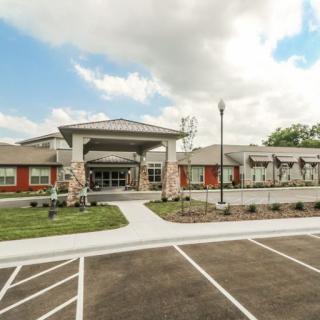 A modern building with a spacious parking lot and a partly cloudy sky overhead.