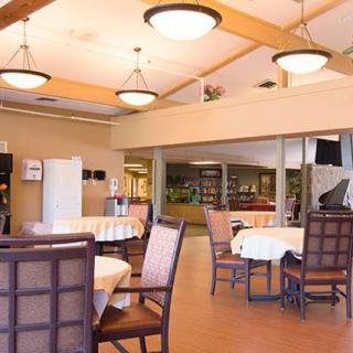 A cozy dining area with neatly arranged tables and chairs, featuring warm lighting.
