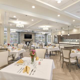 An elegant dining room with neatly arranged tables and chairs, featuring chandeliers and modern decor.