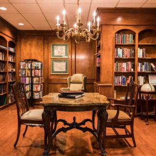A cozy, traditional library with wood paneling and a chandelier.