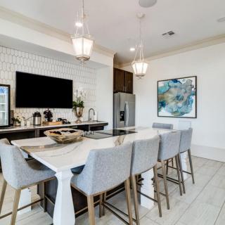 A modern dining area with a marble countertop and bar stools, featuring minimalist decor and pendant lighting.