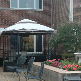 A cozy outdoor gazebo surrounded by vibrant flowers, perfect for relaxation.