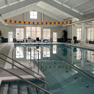 A spacious indoor swimming pool with ample natural light and seating area.