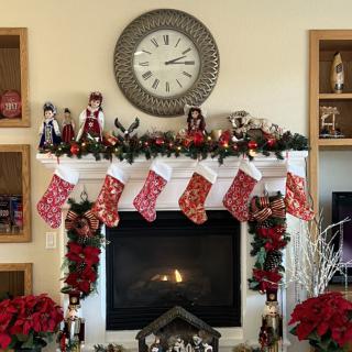 A cozy fireplace decorated for Christmas with stockings, garlands, and poinsettias.