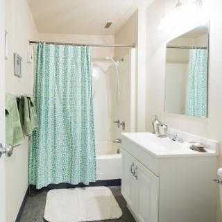 A clean and bright bathroom with a shower and mint green curtain.