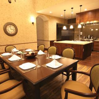 A beautifully arranged dining room featuring a wooden table set for a meal, surrounded by elegant chairs and modern kitchen aesthetics.
