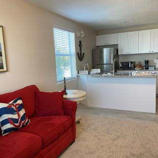 An open concept living room with a red couch and adjacent kitchen area.