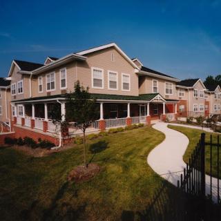 A beautiful residential building surrounded by green lawns and a winding pathway.